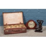 A small leather suitcase along with mantle clock and figure of posed naked woman.