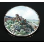 A continental silver and enamel brooch decorated with a landscape scene and castle. 5cm diameter.