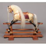 A vintage child's painted wooden rocking horse raised on pine stand. Having glass inset eyes and