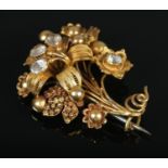 An 18ct gold cannetille work flower brooch set with four paste stones. Maker's mark FM. 4.5cm x 3.