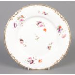 A Rockingham plate decorated with hand painted flowers and gilt border. Red griffin mark C1826-1830.