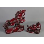 Two red resin figurines of oriental galloping horses. Largest is approx 32cm high.