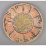 An Islamic Samanid style earthenware dish with Kufic border and central motif. Diameter 32.5cm.