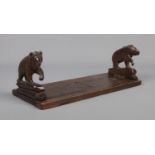 A Black Forest wooden book stand with carved bears to each end.