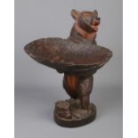 A black forest style carved bear holding dish. Approx. height 39cm. Minor knocks to wood. No signs