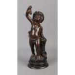 A bronze sculpture modelled as a cherub standing beside a grape hod and holding a bunch of grapes.