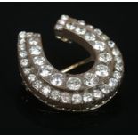 A yellow metal and diamond horse shoe brooch. Set with 44 graduating brilliant cut stones (largest