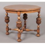 An oak and mahogany circular occasional table with pineapple supports and turned stretcher. Height