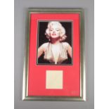 A signed album page by Marilyn Monroe, under colour photo in gold dress, 14cm x 21.5cm, framed and