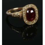 A gold, garnet and diamond ring with scrolled shoulders. Size P 1/2. 4.46g. Tests as 9ct gold.