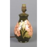A Moorcroft pottery table lamp in the Hibiscus pattern on a green background. Approx 26cm high.