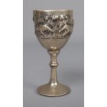 A white metal, possibly silver, goblet featuring rainforest scene with village huts and elephants.