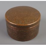 An Eastern circular copper box with extensive engraved decoration. Height 7.5cm, Diameter 12cm.