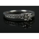 A platinum and diamond ring. The central brilliant cut stone (approximately 0.3ct) flanked by