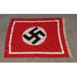 A vintage cotton flag bearing swastika emblem and decorative fringe to one side. Approx.