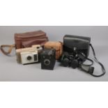 Two cased cameras and a pair of binoculars. Includes a Polaroid J33 Land Camera, Kodak Six-20
