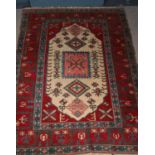 A Turkish carpet featuring the ivory lozenge and geometric motifs framed by wide red borders.