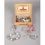 A box containing an assortment of charm bracelets and necklaces including small quantity of silver