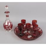 A cranberry glass decanter and serving tray set along with five winter themed glasses.