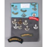 A collection of Durham Light Infantry cap badges and patches including silver and mother of pearl