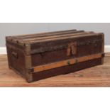 A wooden bound hinged top trunk, with tin base. Height: 32cm Depth: 47cm Width: 83cm.
