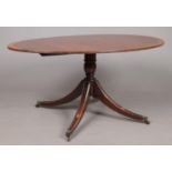 A Regency mahogany tilt top dining table raised on centre pedestal with four splay supports. Label