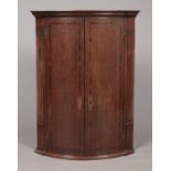 A large Georgian oak bow front corner cupboard with crossbanded doors. With key. Height 96cm,