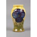 A Moorcroft miniature pottery vase depicting pansies on yellow and green glaze. Height 5.5cm.