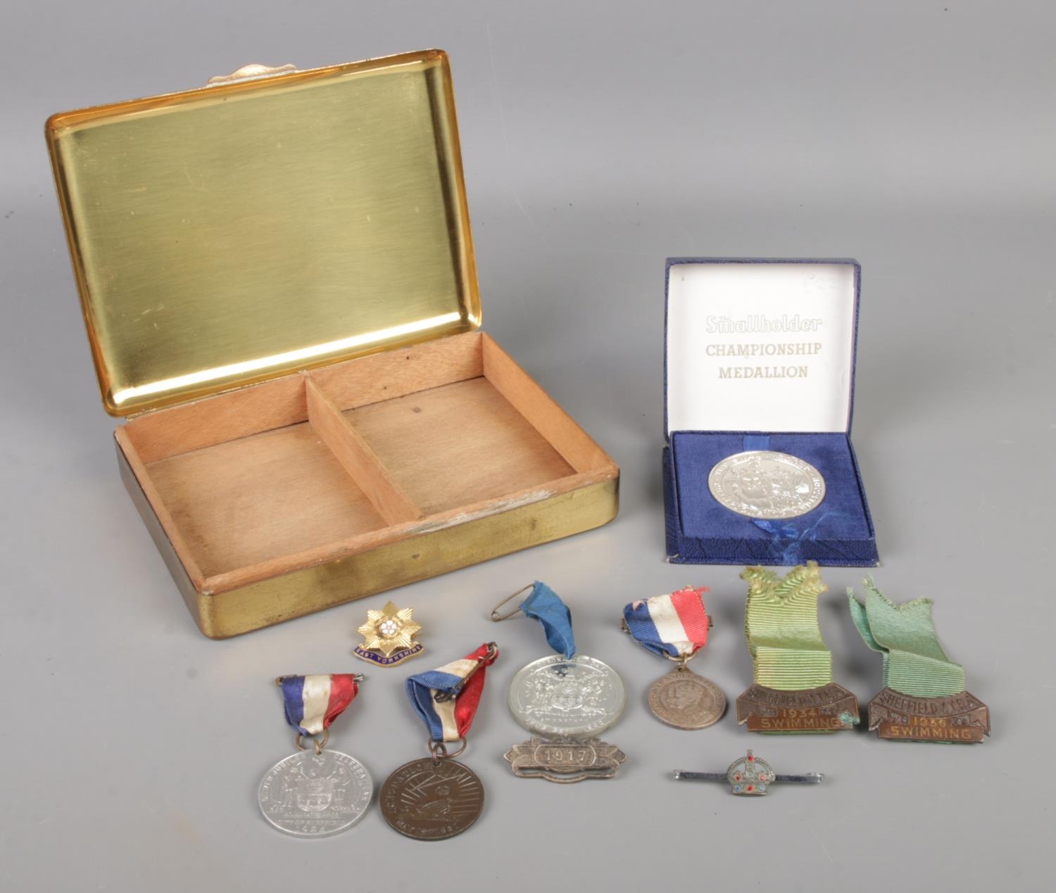 A brass state express box with contents of assorted badges, medallions and metals. To include