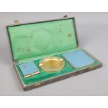 A cased smoking set, including cigarette case, ash tray and match box. Piece missing, perhaps