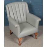 A grey leatherette and studded armchair with mahogany legs.