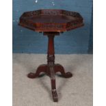 A carved mahogany tripod table with fretwork gallery top and paw feet. Diameter of top 58cm.