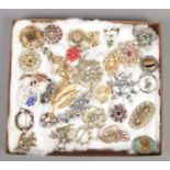 A tray of costume jewellery brooches and scarf clips. Includes locket example, paste set etc. Some