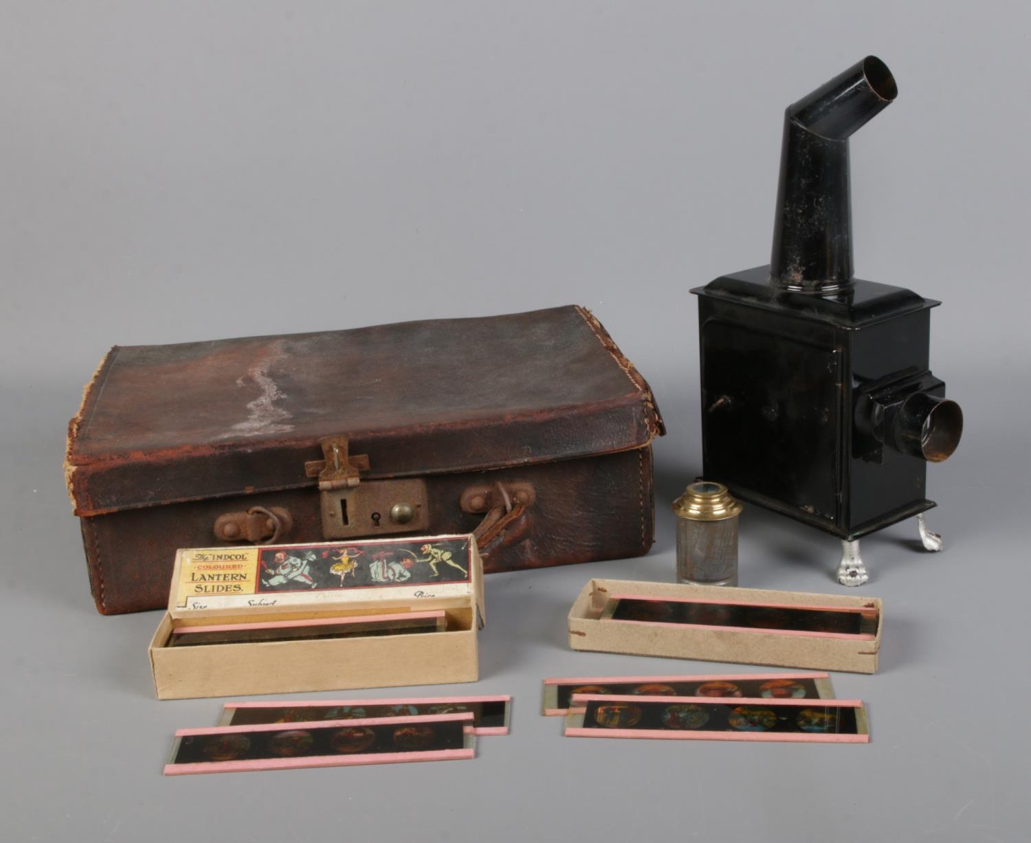 A small magic lantern projector raised on lion paw feet in leather case along with two cases of