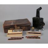 A small magic lantern projector raised on lion paw feet in leather case along with two cases of