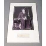 A mounted Paul McCartney autograph display featuring portrait of Beatles performance.