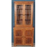 A carved oak lead glazed bookcase with cupboard base. With panelled doors carved with four