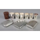 Three white metal hipflasks along with a travelling beaker set.