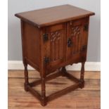 A carved oak Old Charm style side cabinet raised on turned support. (68cm x 51cm)