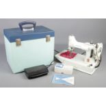 A 1960s white model Singer Featherweight 221K sewing machine with original case and manual.