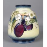 A Moorcroft pottery cream ground vase in the 'Plums' pattern. Stamped VT to base, bearing jug