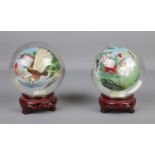 A pair of oriental reverse hand painted spherical glass ornaments depicting eagles and cats, on