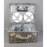 A wicker basket picnic hamper with contents. Featuring four person cutlery set along with fitted