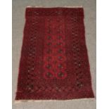 A red ground Persian Bokhara rug with all over geometric design and frilled edge. Length: 183cm,