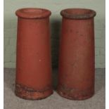 Two cylindrical terracotta chimney pots. Approximately 70cm tall. Ware and tear from being outside.