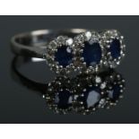 An 18ct white gold, three stone sapphire and diamond ring. Size M. 3.12g.