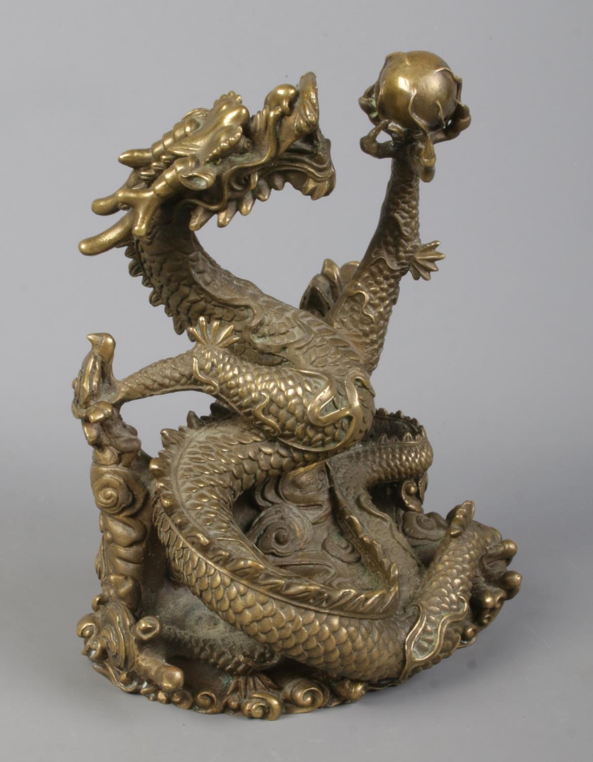 A cast bronze sculpture of a Chinese dragon holding a flaming pearl. Height 18cm.