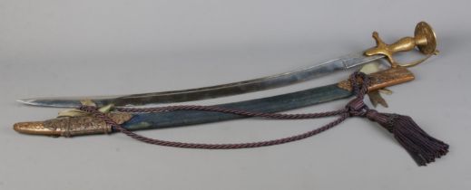 An Indian Tulwar sword with engraved brass handle. The sheath bearing presentation inscription for