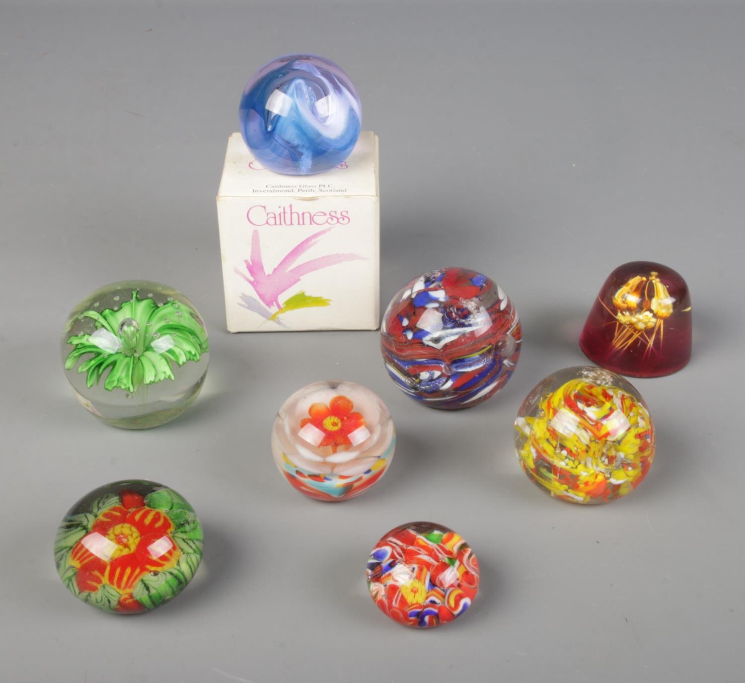 A collection of glass paper weights with one resin example and one boxed Caithness paperweight