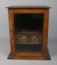 A small oak smokers cabinet with glass door front, pipe racks and two drawers. Approx. dimensions